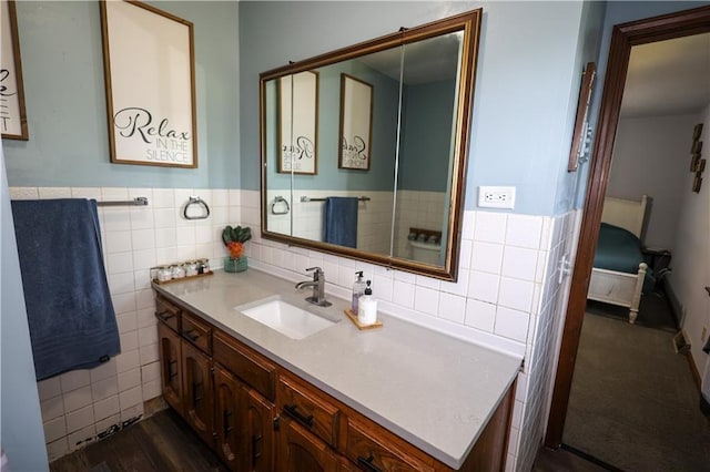 ensuite bathroom featuring a wainscoted wall, connected bathroom, tile walls, and vanity