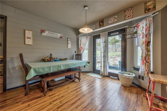 dining space with baseboards, wood finished floors, visible vents, and a textured ceiling