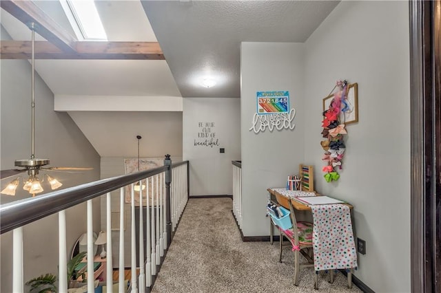 hall featuring baseboards, a textured ceiling, lofted ceiling with skylight, carpet flooring, and an upstairs landing