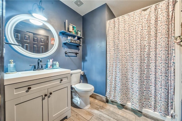 bathroom with visible vents, wood tiled floor, toilet, a shower with curtain, and vanity