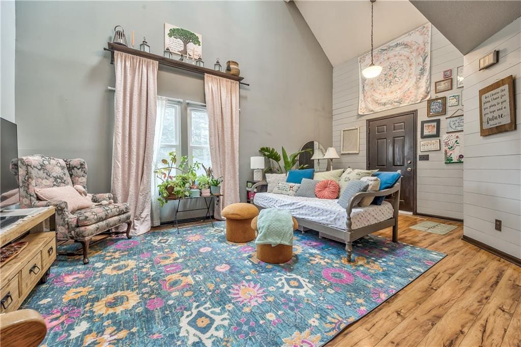 living area with high vaulted ceiling, wood finished floors, and wood walls