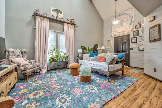 living area with high vaulted ceiling, wood finished floors, and wood walls