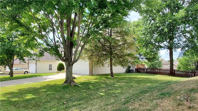 view of yard featuring concrete driveway and fence