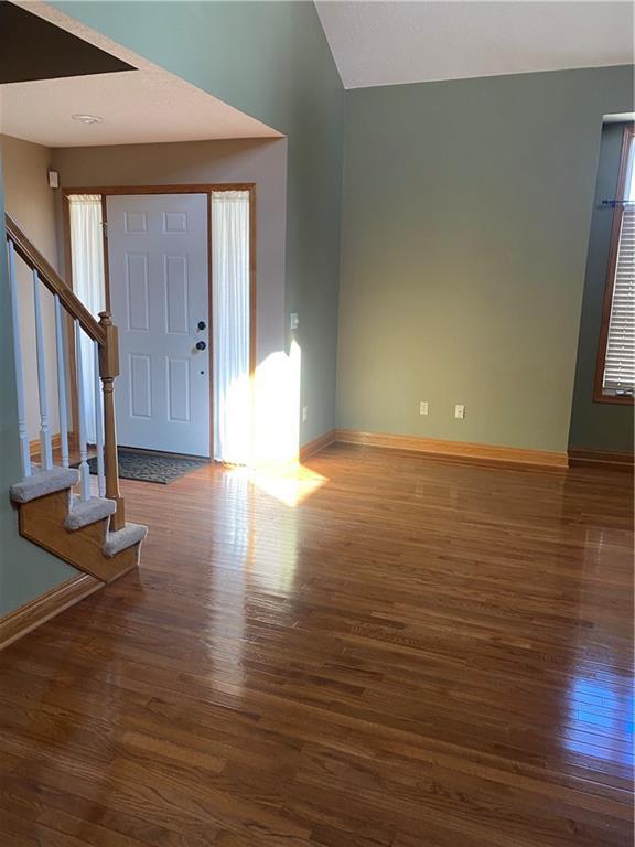 foyer entrance with stairs, baseboards, and wood finished floors