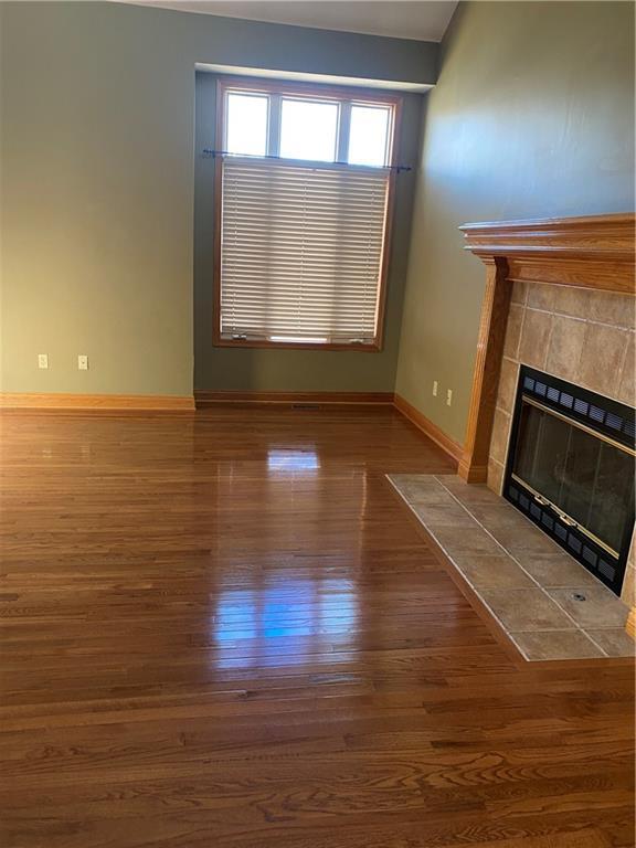 unfurnished living room with wood finished floors, a fireplace, and baseboards