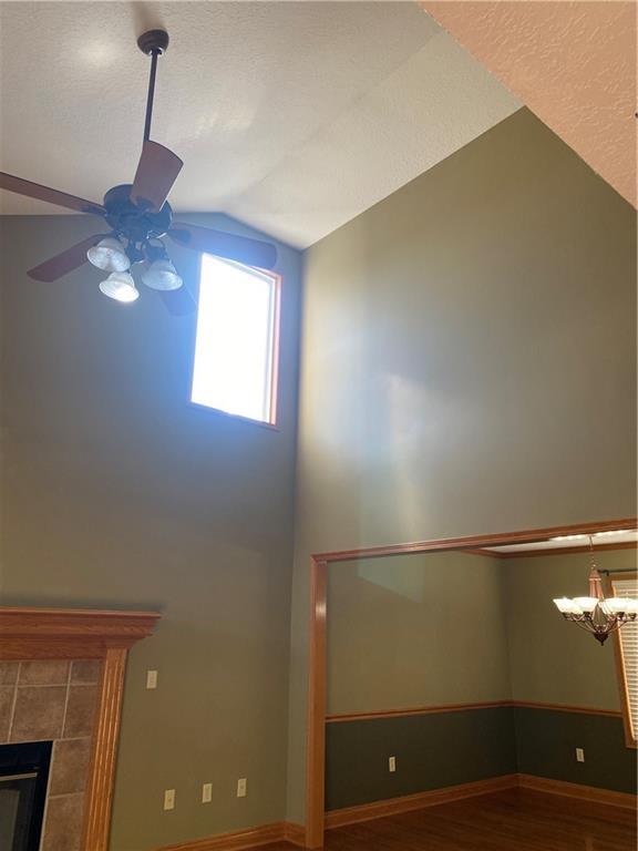 interior space with baseboards, lofted ceiling, a tile fireplace, wood finished floors, and a ceiling fan