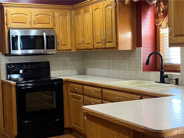 kitchen featuring stainless steel microwave, electric range, light countertops, and a sink