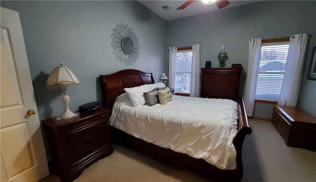 bedroom featuring multiple windows, light colored carpet, and a ceiling fan