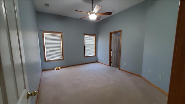 carpeted empty room with visible vents, a ceiling fan, and baseboards