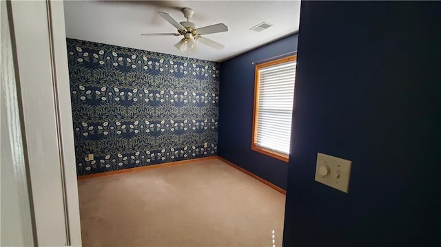 carpeted spare room featuring visible vents, baseboards, a ceiling fan, and wallpapered walls