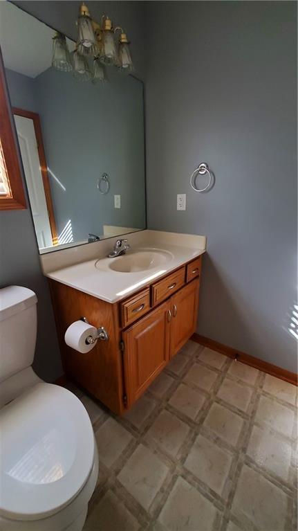 half bathroom with tile patterned floors, toilet, vanity, and baseboards