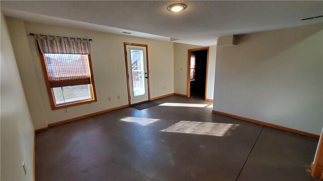 unfurnished room with visible vents, baseboards, and concrete floors