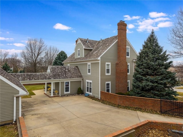 back of property featuring a chimney and fence