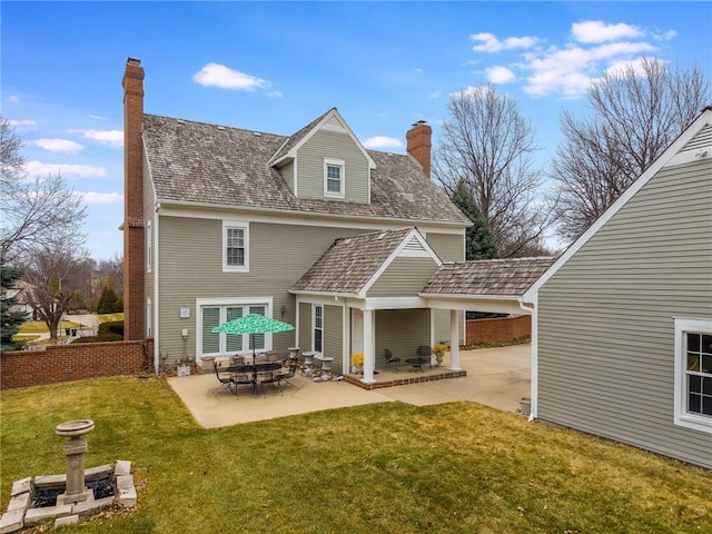 rear view of property with a lawn, a chimney, and a patio area