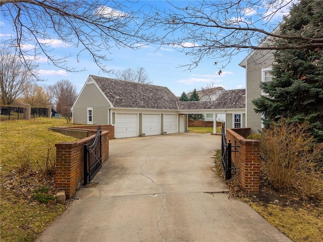 exterior space featuring a detached garage, fence, a yard, an outbuilding, and a gate