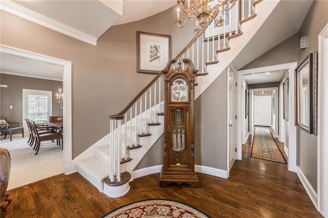 stairway with wood finished floors, baseboards, an inviting chandelier, ornamental molding, and a towering ceiling