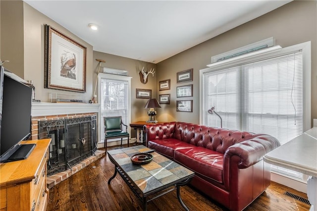 living area featuring visible vents, a fireplace, and wood finished floors