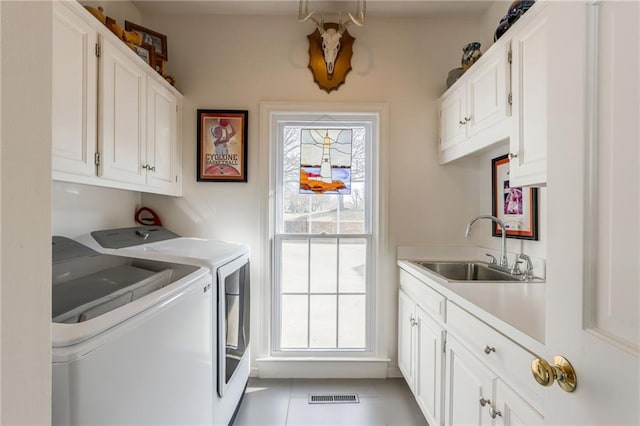 laundry room with a sink, cabinet space, a healthy amount of sunlight, and washer and dryer