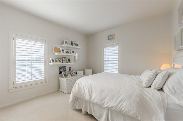 bedroom featuring multiple windows, light colored carpet, and baseboards