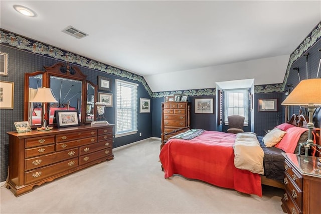 bedroom with wallpapered walls, lofted ceiling, multiple windows, and visible vents