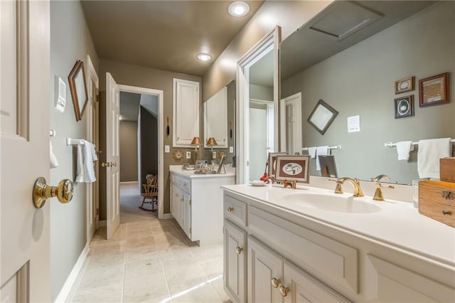 bathroom featuring a sink, baseboards, two vanities, and tile patterned flooring