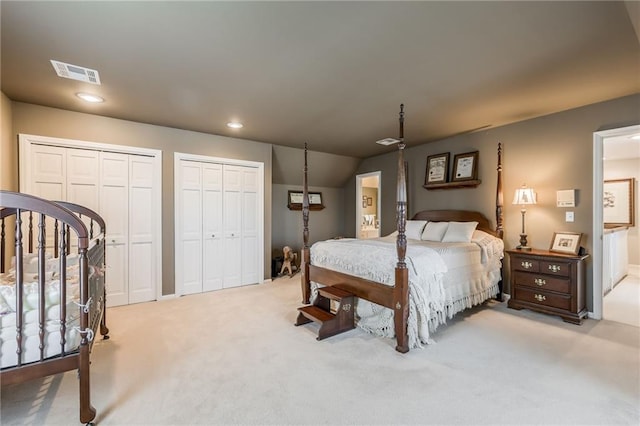 bedroom with recessed lighting, visible vents, two closets, and light carpet