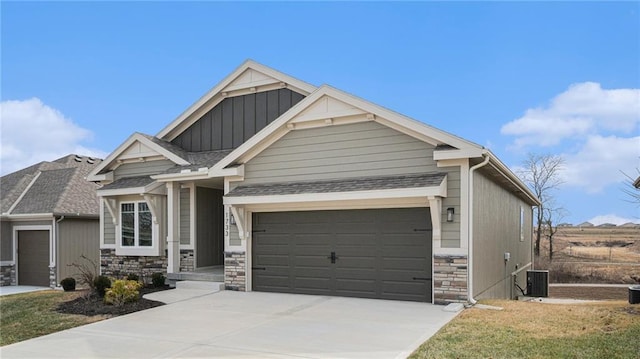 craftsman-style home featuring driveway, central AC unit, stone siding, an attached garage, and board and batten siding