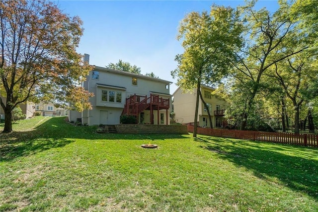 rear view of house featuring fence, a lawn, and a wooden deck