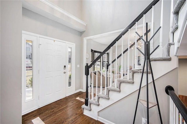 foyer entrance with plenty of natural light, stairway, a towering ceiling, and wood finished floors