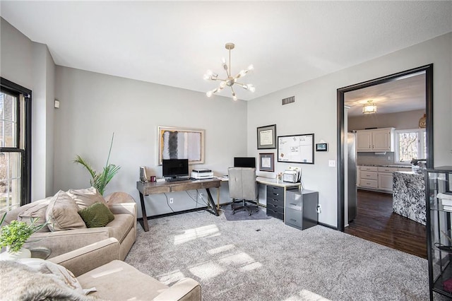 office space with visible vents, dark carpet, baseboards, and an inviting chandelier