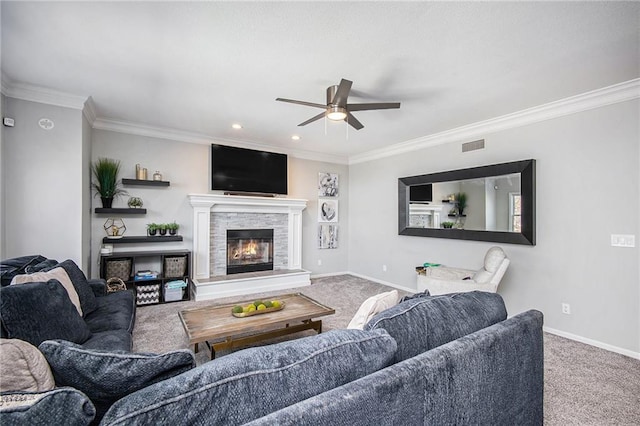 living area with a glass covered fireplace, baseboards, ornamental molding, and carpet flooring