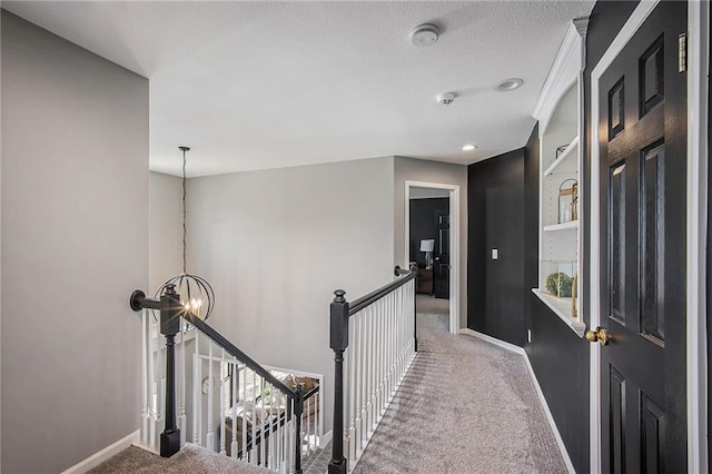 hallway featuring baseboards, an upstairs landing, a notable chandelier, and carpet floors