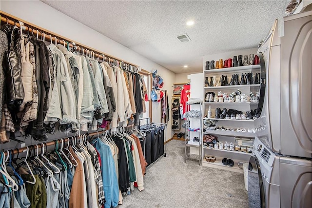 spacious closet featuring stacked washer and dryer, visible vents, and light carpet