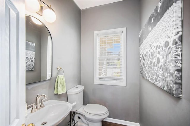 bathroom with toilet, baseboards, and a sink