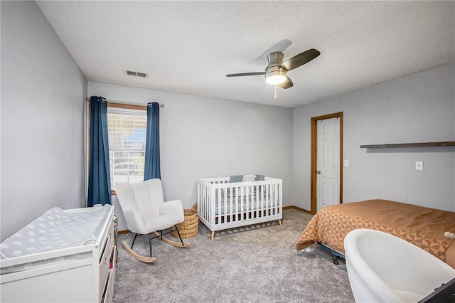 carpeted bedroom with visible vents, baseboards, a textured ceiling, and a ceiling fan