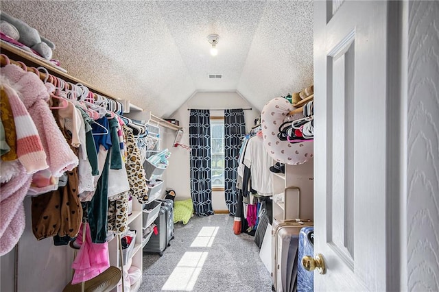 walk in closet featuring lofted ceiling, visible vents, and carpet floors