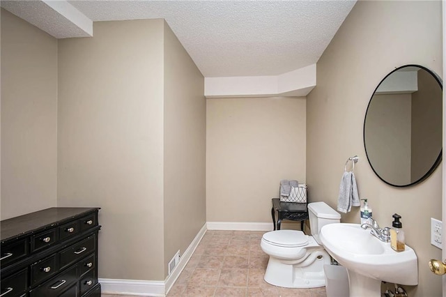 bathroom with tile patterned floors, visible vents, toilet, a textured ceiling, and baseboards