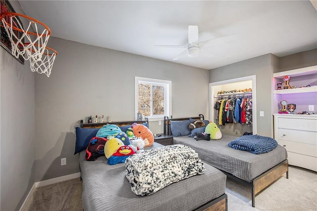 carpeted bedroom featuring a walk in closet, baseboards, a closet, and ceiling fan