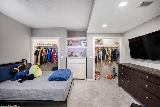 bedroom featuring a spacious closet, light colored carpet, visible vents, and a closet