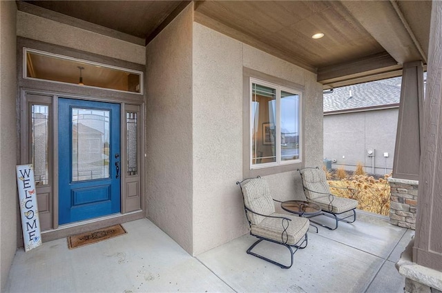 entrance to property with covered porch and stucco siding