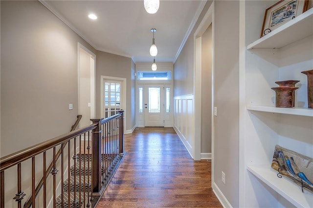 entryway featuring baseboards, ornamental molding, a decorative wall, and wood finished floors