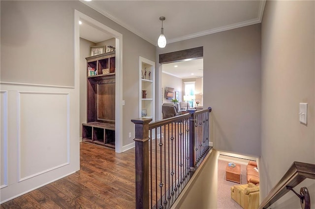 corridor featuring built in features, wood finished floors, an upstairs landing, and crown molding