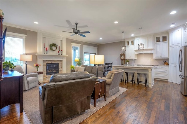 living room with ornamental molding, dark wood finished floors, a glass covered fireplace, and recessed lighting