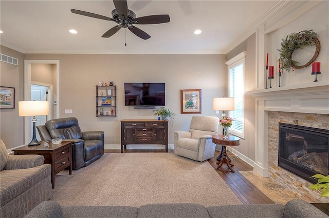 living area with baseboards, visible vents, ornamental molding, wood finished floors, and a fireplace