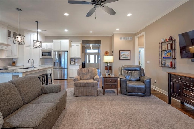 living room featuring baseboards, wood finished floors, visible vents, and crown molding