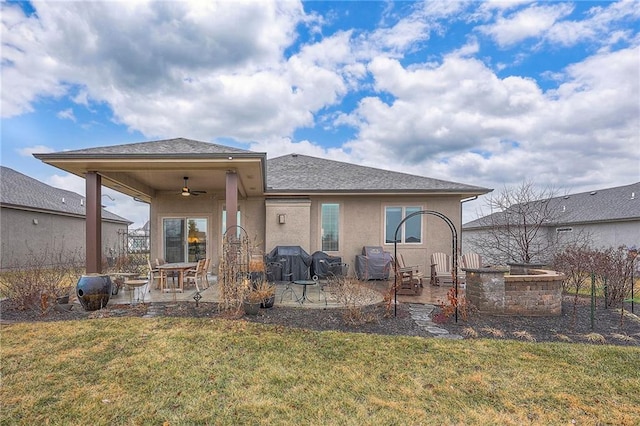 back of house with ceiling fan, a patio area, a lawn, and stucco siding