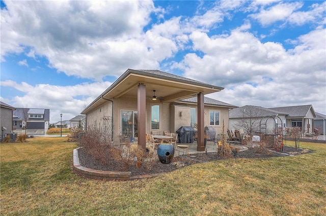 back of house featuring a yard, a patio area, a ceiling fan, and stucco siding