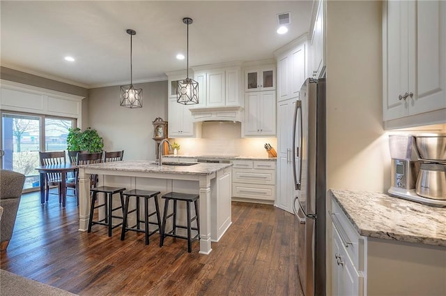 kitchen with visible vents, decorative backsplash, freestanding refrigerator, a sink, and a kitchen bar