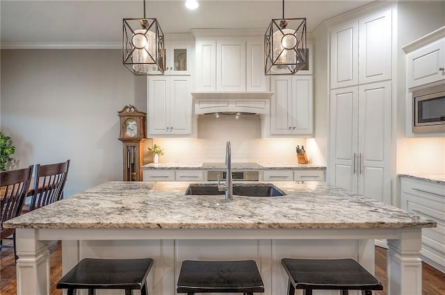 kitchen with ornamental molding, white cabinets, stainless steel microwave, and backsplash