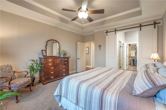 bedroom with carpet floors, a barn door, a tray ceiling, and crown molding